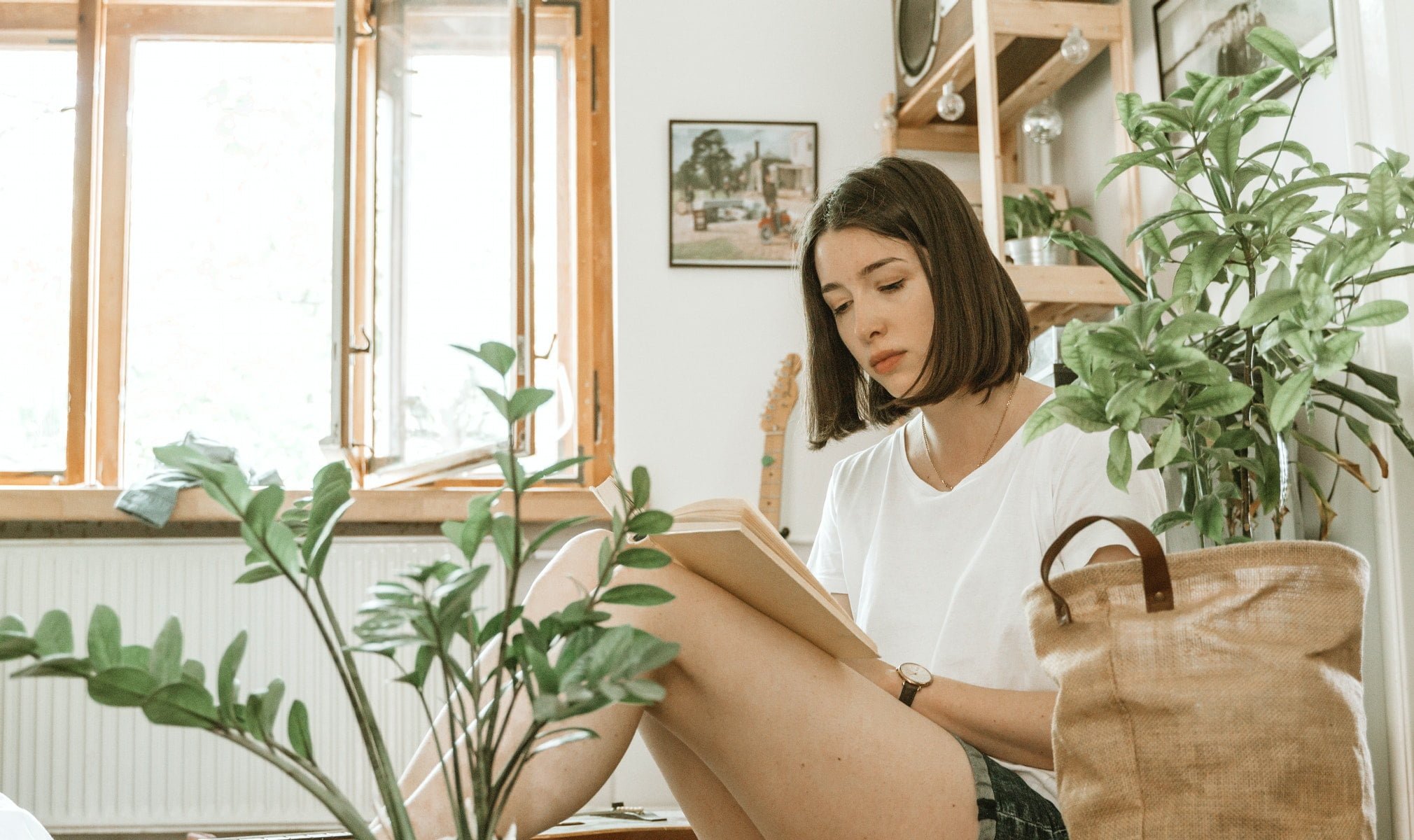 A woman reading next to plants